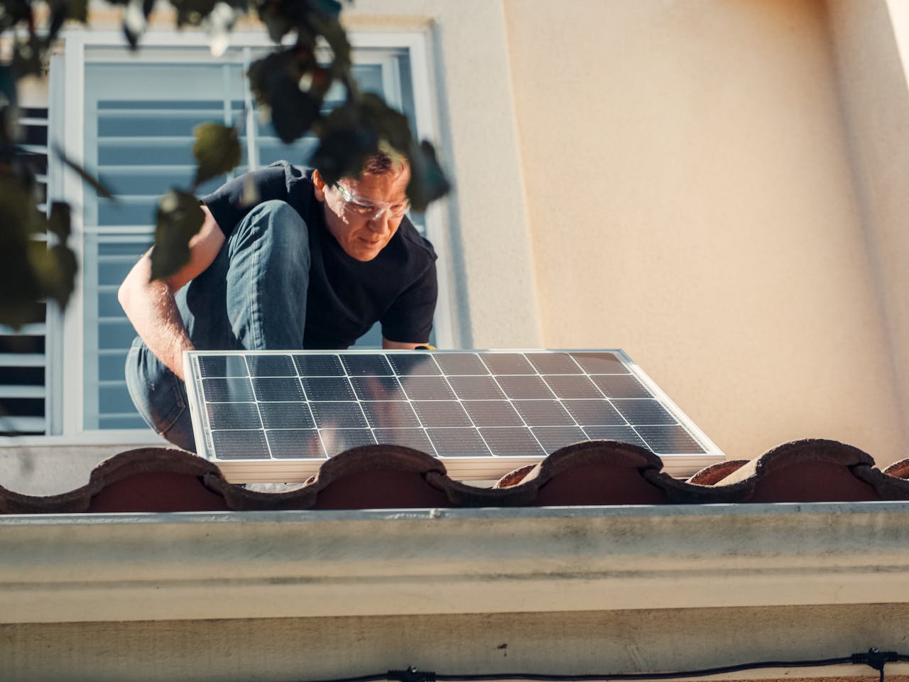 A technician installs a solar panel on a house roof, embracing clean energy solutions.