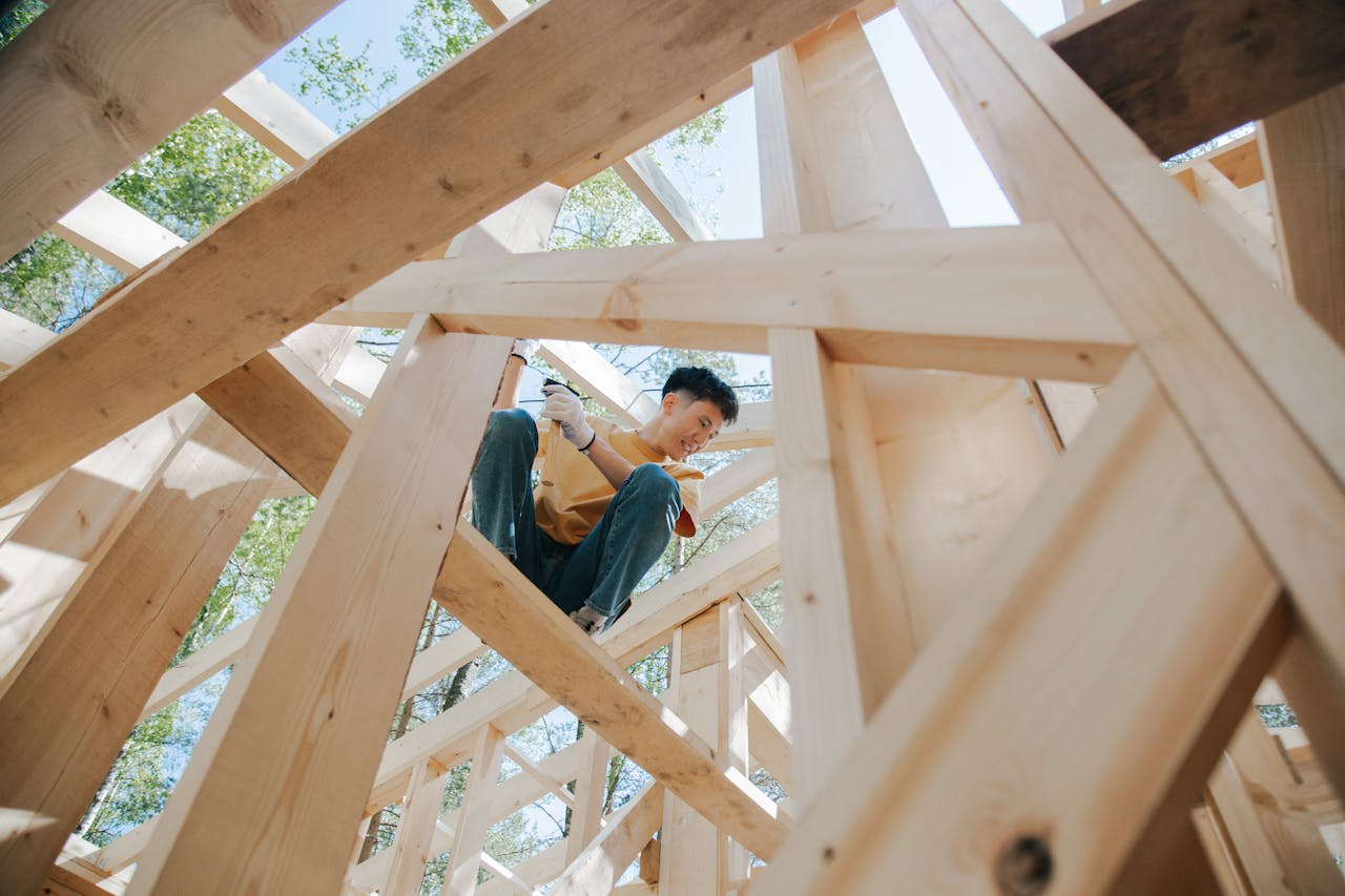 Services-02 Carpenter working on the wooden structure of a house at a construction site under the sun.